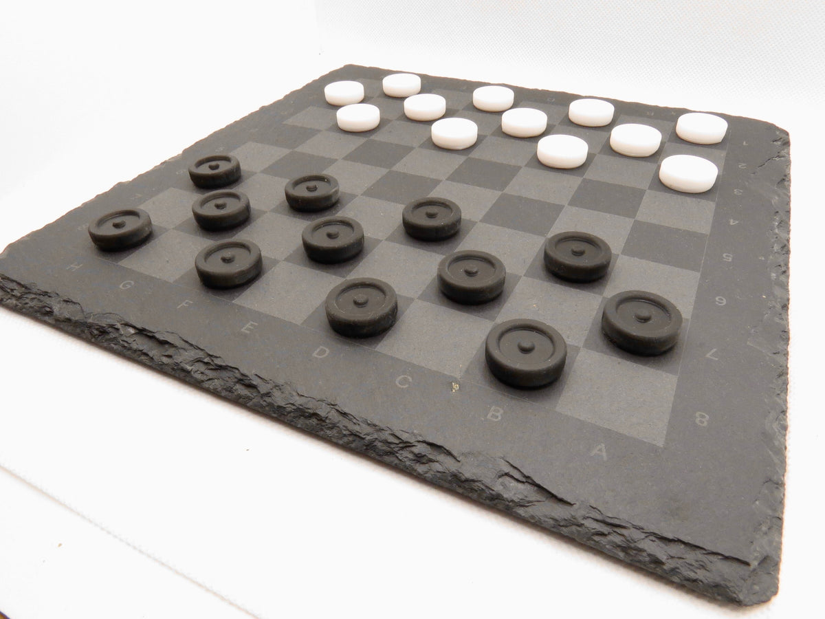 Aufgebautes Dame-Spiel seitlich: Modernes Design des Strategie-Klassikers auf grauer Steinplatte.