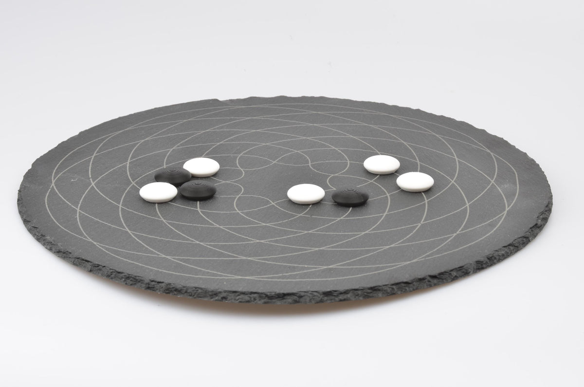 Go Strategie-Spiel Aufbau: Platzierte Spielsteine auf dem runden Design-Brett in Spielsituation.